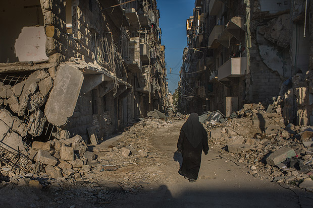 Moradores de Aleppo caminham pela cidade quase totalmente destruda por batalhas e bombardeios