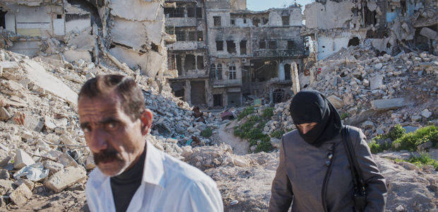 Casal passa por meio de escombros de bairro da cidade de Aleppo