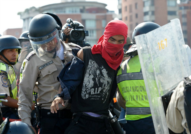 Policiais prendem manifestante em protesto contra Nicolás Maduro em Caracas na segunda-feira (24)