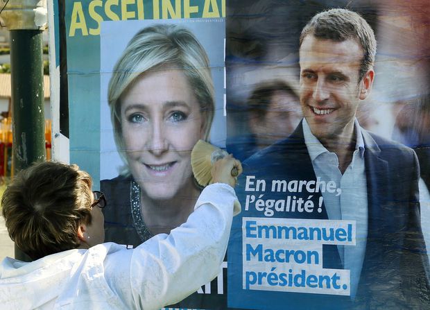 Apoiadora de Macron cola cartaz do centrista ao lado do de Marine Le Pen em Saint-Jean-de-Luz, sudoeste francês
