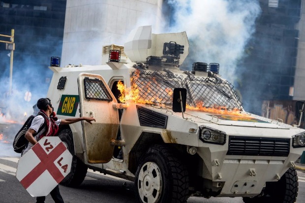 Guardas abrem porta de blindado atingido por coquetel molotov atirado por encapuzados em Caracas
