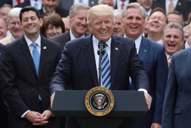 O presidente Donald Trump sorri ao lado dos legisladores aps aprovao do fim do Obamacare