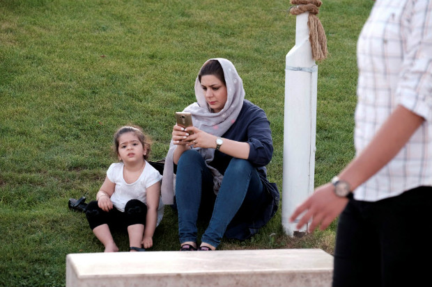 Iraniana usa celular em Teer; antes refratrios, conservadores usam redes sociais para atacar rivais