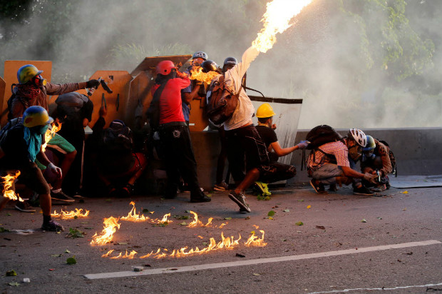 Manifestante encapuzado atira coquetel molotov em confronto com guardas nacionais em Caracas