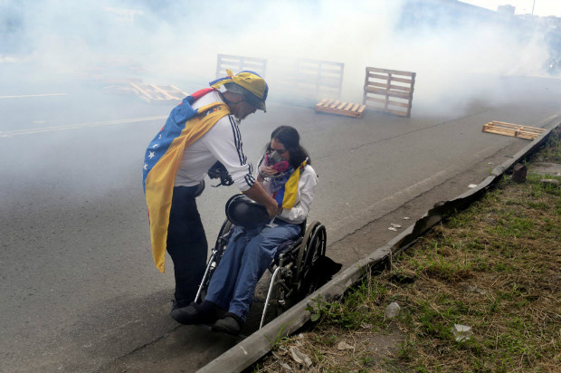 Homem ajuda mulher em cadeira de rodas durante protesto contra Nicols Maduro em Caracas