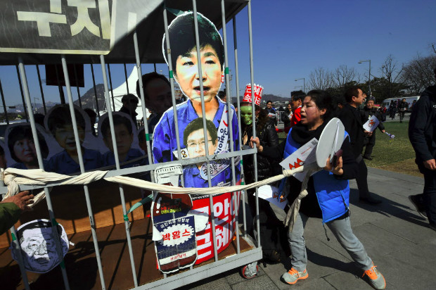 Manifestantes carregam cela falsa com boneco de Park Geun-hye em protesto na Coreia do Sul