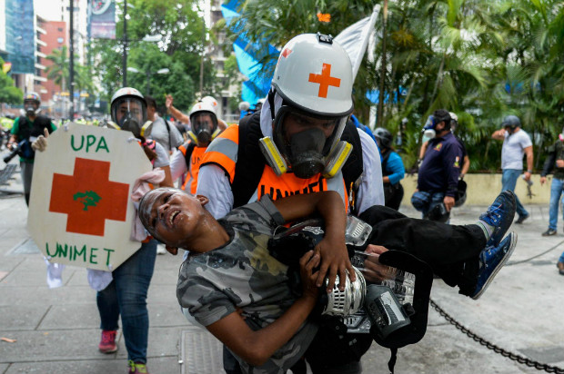 Paramdicos voluntrios carregam adolescente ferido em protesto contra Nicols Maduro em Caracas