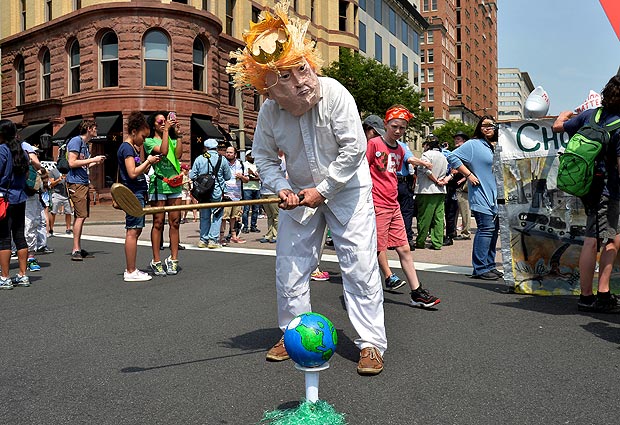 FILE PHOTO: A protester in a costume depicting Trump sets an Earth on a tee as he holds a golf club while joining demonstrators moving down Pennsylvania Avenue during a People's Climate March, to protest U.S. President Donald Trump's stance on the environment, in Washington, U.S., April 29, 2017. REUTERS/Mike Theiler/File Photo ORG XMIT: ROP330