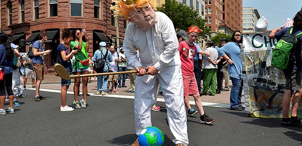 FILE PHOTO: A protester in a costume depicting Trump sets an Earth on a tee as he holds a golf club while joining demonstrators moving down Pennsylvania Avenue during a People's Climate March, to protest U.S. President Donald Trump's stance on the environment, in Washington, U.S., April 29, 2017. REUTERS/Mike Theiler/File Photo ORG XMIT: ROP330