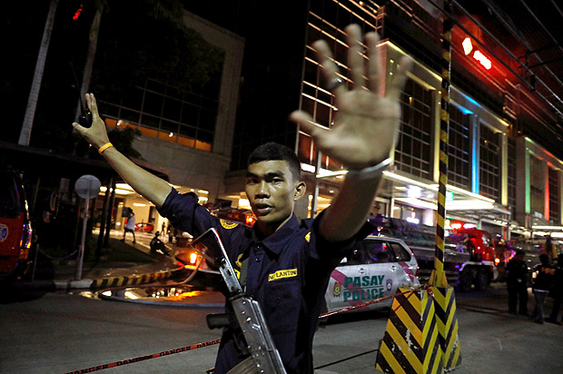 Policial barra passagem de pessoas perto de resort alvo de ataque em Manila, nas Filipinas