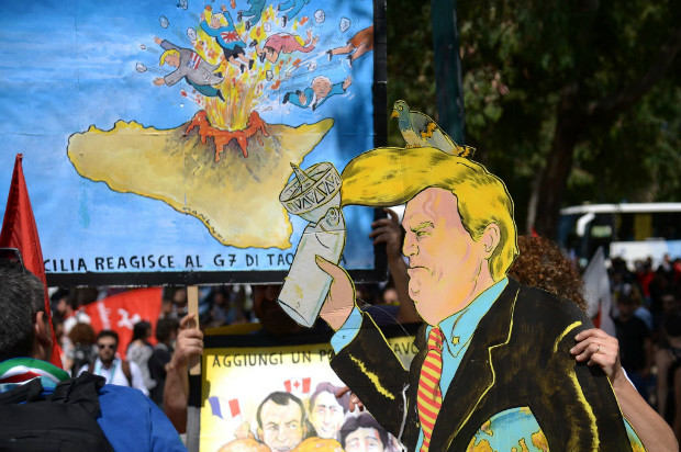 Manifestante carrega cartaz com caricatura de Donald Trump em protesto contra reunio do G7 na Itlia