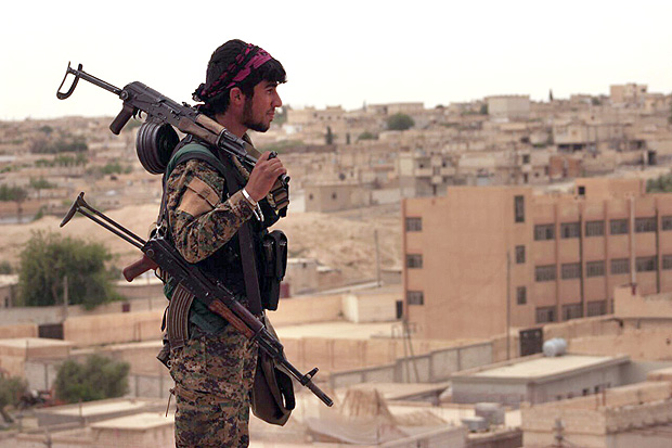 FILE - In this Sunday, April 30, 2017, file photo, provided by the Syria Democratic Forces (SDF), shows a fighter from the SDF carrying weapons as he looks toward the northern town of Tabqa, Syria. A U.S. military official says the offensive against the Islamic State group's de facto capital, Raqqa "will be long and difficult." Lt. Gen. Steve Townsend, the top U.S. commander in Iraq, says the assault by the Syrian Democratic Forces will deliver a decisive blow to the idea of IS "as a physical caliphate." The Kurdish-led force launched an offensive to capture Raqqa on Tuesday.(Syrian Democratic Forces, via AP, File) ORG XMIT: CAIMA102