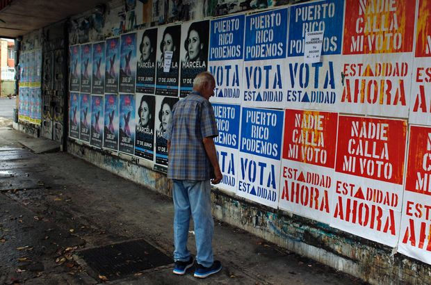 A man reads campaign posters promoting Puerto Rico's statehood in San Juan, on June 9, 2017. A referendum on the political status of the US territory takes place on June 11, 2017. The US commonwealth of Puerto Rico votes on whether to become the 51st state. / AFP PHOTO / Ricardo ARDUENGO