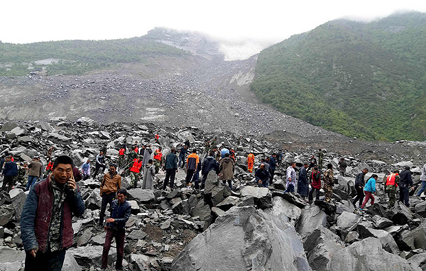 TOPSHOT - CORRECTION - Chinese military police and rescue workers are seen at the site of a landslide in in Xinmo village, Diexi town of Maoxian county, Sichuan province on June 24, 2017. Around 100 people are feared buried after a landslide smashed through their village in southwest China's Sichuan Province early Saturday, local officials said, as they launched an emergency rescue operation. / AFP PHOTO / STR / China OUT / 