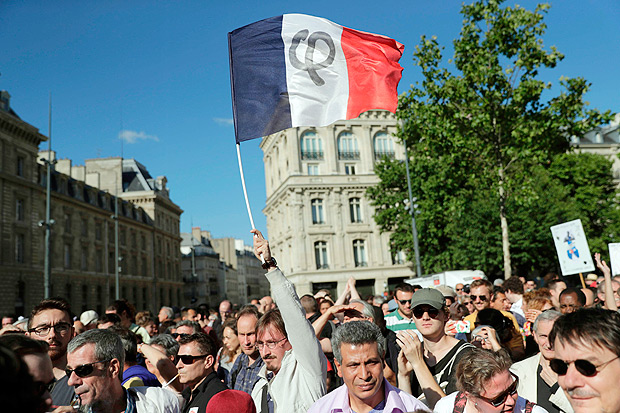 People gather and wave a French national flag as they listen to La France Insoumise (LFI) leftist party's leader delivering a speech on Place de la Republique on July 3, 2017 in Paris, in reaction to the French President's address to members of the National Assembly and Senate since his election. LFI leader Jean-Luc Melenchon organized a gathering in Paris on July 3 instead of attending President Emmanuel Macron's address to members of Parliament at the Versailles palace. / AFP PHOTO / Thomas SAMSON