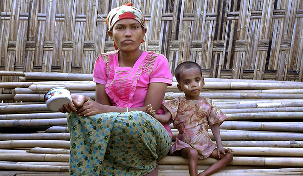 In this Friday, March 17, 2017, image made from video, Rosmaida Bibi, right, who suffers from severe malnutrition, sits with her 20-year old mother Hamida Begum outside their makeshift shelter at the Dar Paing camp, north of Sittwe, Rakhine State, Myanmar. Rosmaida Bibi looks a lot like any of the underfed 1-year-olds in a squalid camp for Myanmar's displaced ethnic Rohingya minority - but she's 4. She cannot grow, and her mother can't find anyone to help her because authorities won't let Rohingya leave the camp. (AP Video) ORG XMIT: XGA104
