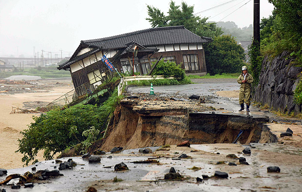 A resident checks a collapsed road side neaer a damaged house following heavy flooding in Asakura, Fukuoka prefecture, on July 7, 2017. Huge floods engulfing parts of southern Japan are reported to have killed at least six people and left hundreds stranded as the torrents swept away roads and houses and destroyed schools. / AFP PHOTO / KAZUHIRO NOGI ORG XMIT: KN661