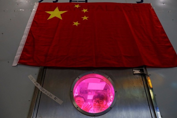 Voluntário acena de cabine que simula o ambiente espacial na Universidade Beihang, em Pequim