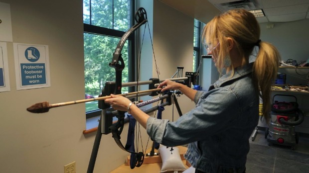 Estudante da Universidade de Kent carrega arco com uma flecha; pesquisadores reproduzem armas