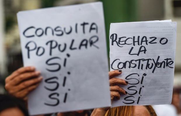 Manifestantes seguram cartazes em defesa do plebiscito e contra a Constituinte na Venezuela