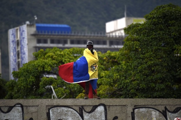 Ativista da oposio enrolado em bandeira da Venezuela protesta contra Nicols Maduro em Caracas