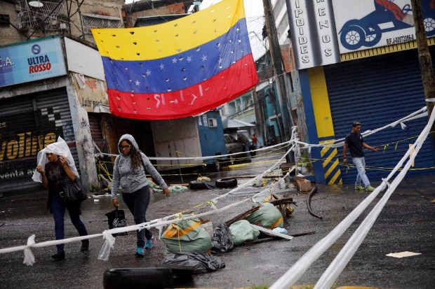 Pedestres tentam ultrapassar barricada montada por opositores a Nicols Maduro em rua de Caracas