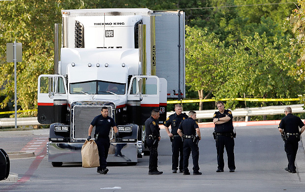 San Antonio police officers investigate the scene Sunday, July 23, 2017, where eight people were found dead in a tractor-trailer loaded with at least 30 others outside a Walmart store in stifling summer heat in what police are calling a horrific human trafficking case, in San Antonio. (AP Photo/Eric Gay) ORG XMIT: TXEG102