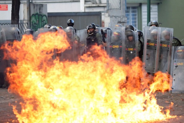 Guardas Nacionais se protegem aps manifestantes atirarem coquetel molotov em protesto em Caracas