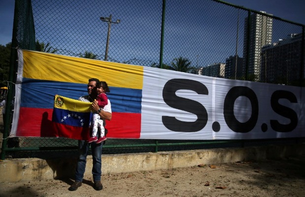 Venezuelano tira foto ao lado de faixa pedindo socorro em centro de votao do plebiscito no Rio