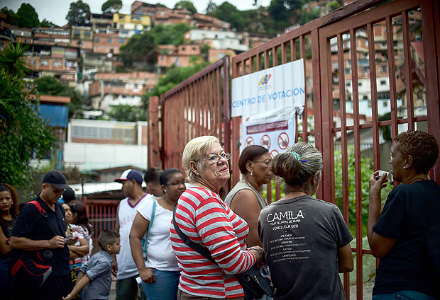 People queue to cast their vote to elect a Constituent Assembly in Caracas on July 30, 2017. Polls opened in Venezuela on Sunday for the election of a new, all-powerful "Constituent Assembly" that President Nicolas Maduro promised would end his country's political and economic crisis by rewriting the constitution. / AFP PHOTO / RONALDO SCHEMIDT ORG XMIT: RSA208