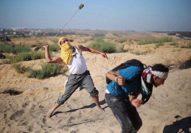 Jovens palestinos atiram pedras contra soldados de Israel em confronto na fronteira com a faixa de Gaza