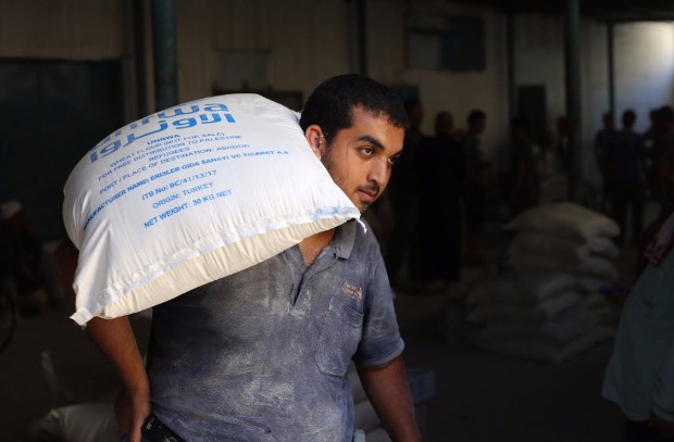 Homem palestino carrega saco de ajuda humanitária da ONU em campo de refugiados de Gaza