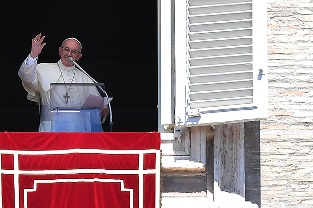 Pope Francis waves to the crowd from the window of the apostolic palace overlooking St Peter's square during the Sunday Angelus prayer, on August 13, 2017 in Vatican. / AFP PHOTO / Alberto PIZZOLI