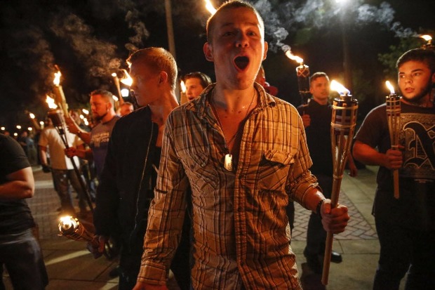 In this photo taken Friday, Aug. 11, 2017, multiple white nationalist groups march with torches through the UVA campus in Charlottesville, Va. Hundreds of people chanted, threw punches, hurled water bottles and unleashed chemical sprays on each other Saturday after violence erupted at a white nationalist rally in Virginia. (Mykal McEldowney/The Indianapolis Star via AP) ORG XMIT: ININS102