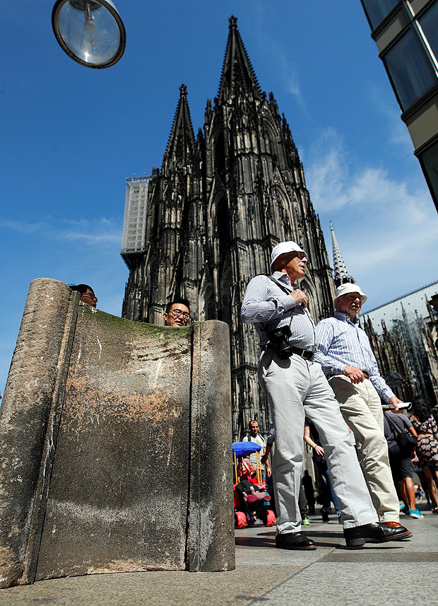 People walk past concrete barriers placed by police in front of the world famous gothic cathedral in Cologne, Germany, August 23, 2017. REUTERS/Wolfgang Rattay ORG XMIT: JOH02