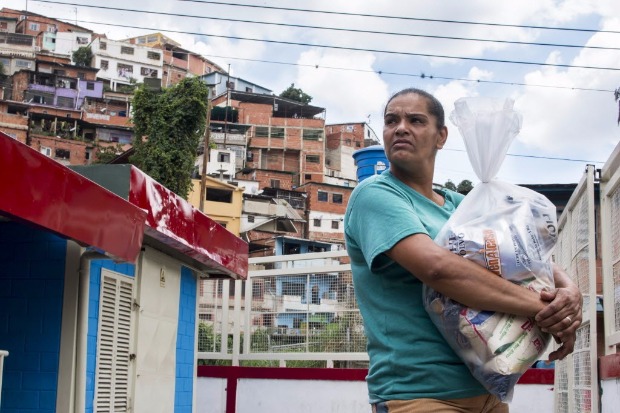 Beneficiria deixa centro de abastecimento com sua cesta bsica em Macarao, no oeste de Caracas