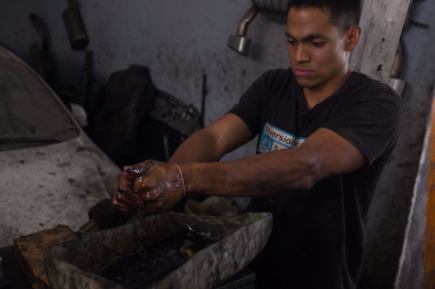 O mecnico Luiz Ramirez, 31, lava mos com gasolina pura para retirar a graxa em oficina de Caracas
