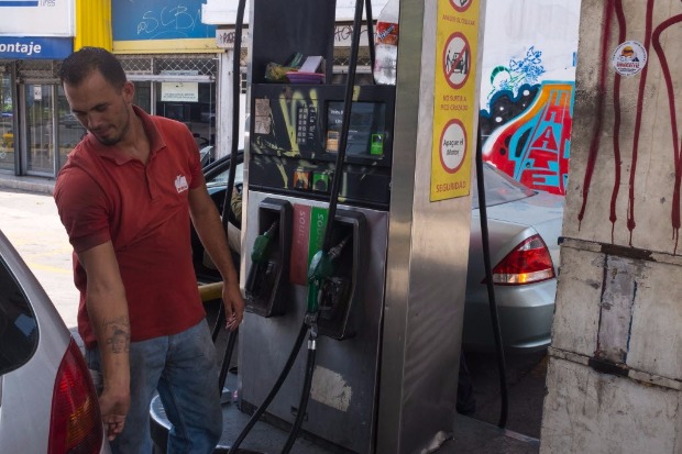 Frentista enche o tanque de um carro em Caracas; com US$ 0,01 pode-se comprar 160 litros de gasolina
