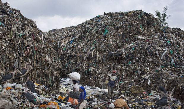 Homens e mulheres coletam materiais reciclveis em meio a pilha de lixo e sacos plsticos em Nairobi, no Qunia
