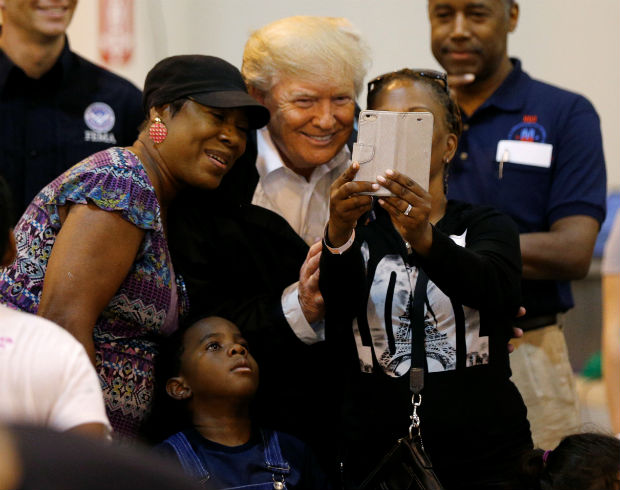 Em abrigo para desalojados por furacões, o presidente Donald Trump posa para foto com a família que sobreviveu à tempestade tropical Harvey 
