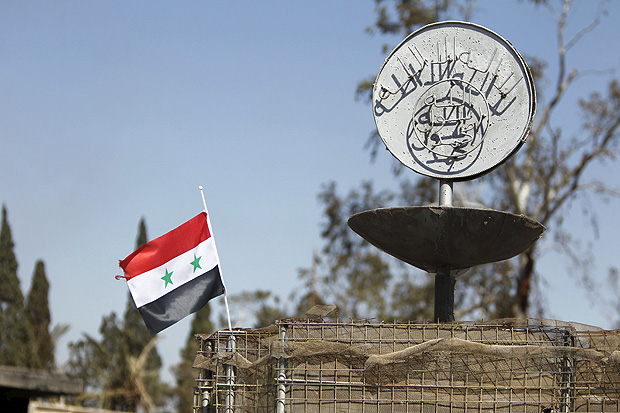 A Syrian national flag flutters next to the Islamic State's slogan at a roundabout where executions were carried out by ISIS militants in the city of Palmyra, in Homs Governorate, Syria April 1, 2016. REUTERS/Omar Sanadiki SEARCH 