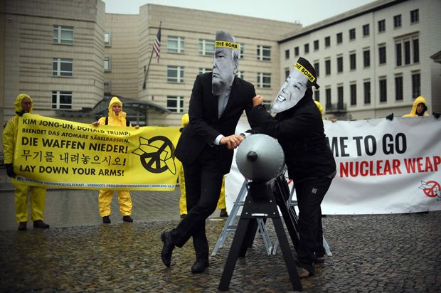 Activists of the non-governmental organization "International Campaign to Abolish Nuclear Weapons (ICAN)" wear masks of US President Donal Trump and leader of the Democratic People's Republic of Korea Kim Jon-un while posing with a mock missile in front of the embassy of Democratic People's Republic of Korea in Berlin, on September 13, 2017. / AFP PHOTO / dpa / Britta Pedersen / Germany OUT ORG XMIT: 90-014441