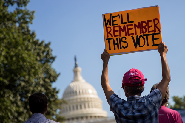 WASHINGTON, DC - JULY 26: A protestor holds up a sign during a rally against the GOP health care plan, on Capitol Hill, July 26, 2017 in Washington, DC. GOP efforts to pass legislation to repeal and replace the Affordable Care Act, also known as Obamacare, were dealt setbacks when a mix of conservative and moderate Republican senators joined Democrats to oppose procedural measures on the bill. Drew Angerer/Getty Images/AFP == FOR NEWSPAPERS, INTERNET, TELCOS & TELEVISION USE ONLY ==
