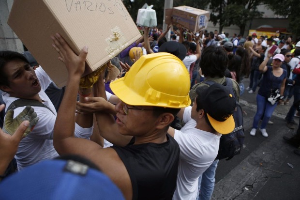 Voluntrios carregam caixas de suprimentos mdicos ao lado de prdio derrubado na Cidade do Mxico
