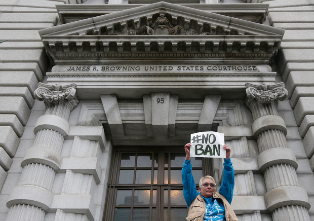 FILE- In this Feb. 7, 2017, file photo, Karen Shore holds up a sign outside of the 9th U.S. Circuit Court of Appeals in San Francisco. The appeals court on Thursday, Sept. 7, rejected the Trump administration's limited view of who is allowed into the United States under the president's travel ban, saying grandparents, cousins and similarly close relations of people in the U.S. should not be prevented from coming to the country. (AP Photo/Jeff Chiu, File) ORG XMIT: PDX411