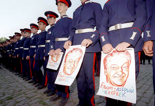 Soldados cossacos seguram pster de Boris Ieltsin na chegada do candidato  cidade, em 1996