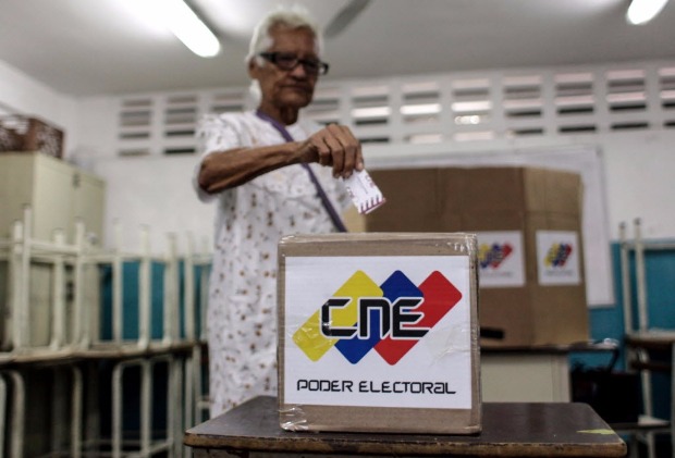 Eleitora coloca sua cdula de votao de papel em uma urna aps votar no Estado de Miranda