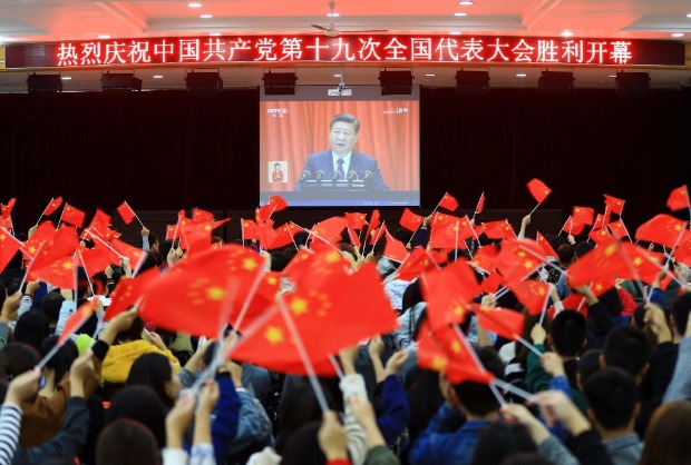 Estudantes balanam bandeiras ao acompanhar fala de Xi Jinping no Congresso do Partido Comunista
