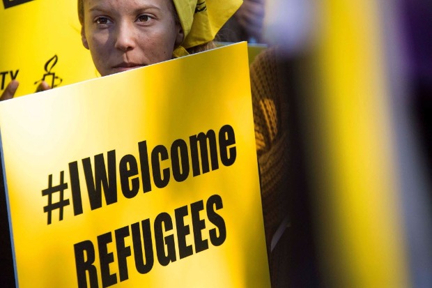 Manifestante segura cartaz em defesa dos refugiados em protesto contra decreto anti-imigração de Trump