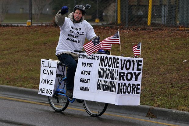 A man yells "Keep Alabama red" as he rides his bike with signs of support for Alabama Republican senatorial candidate Roy Moore around a venue that will host U.S. President Donald Trump later in the day in Pensacola, Florida, U.S., December 8, 2017. REUTERS/Carlo Allegri ORG XMIT: NYC101